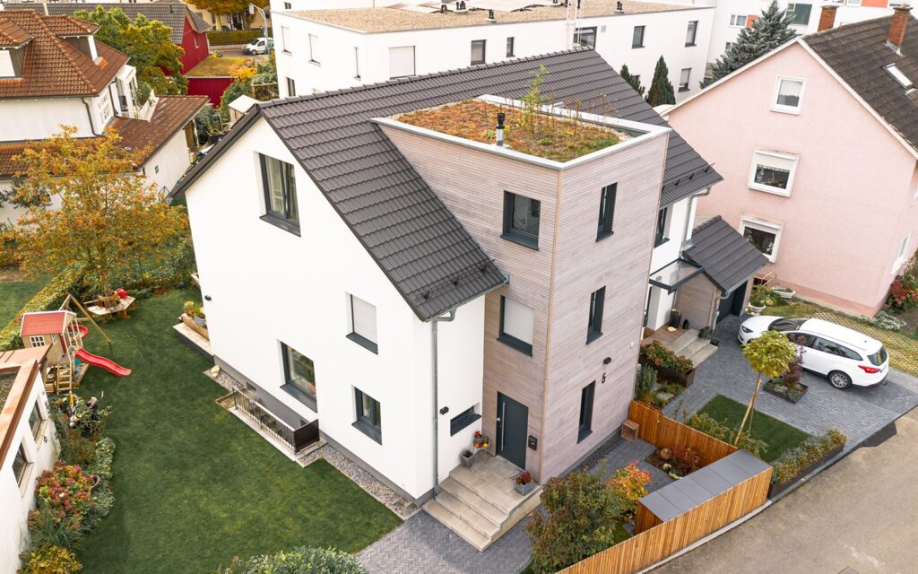 Gesamtansicht des Hauses mit gepflegtem Vorgarten, Spielbereich und hellgrauer Einfahrt in ruhigem Wohngebiet.