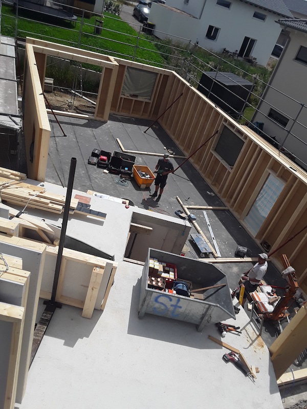 Blick von oben auf eine Baustelle im Holzrahmenbau, Handwerker arbeiten am Rohbau des Erdgeschosses.